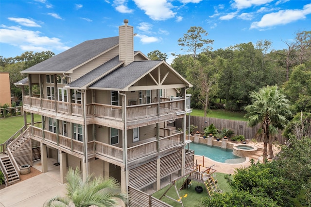 back of property with a patio area, a pool with hot tub, and a balcony