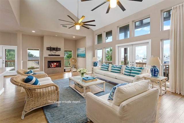 living room featuring light hardwood / wood-style flooring, a healthy amount of sunlight, high vaulted ceiling, and ceiling fan