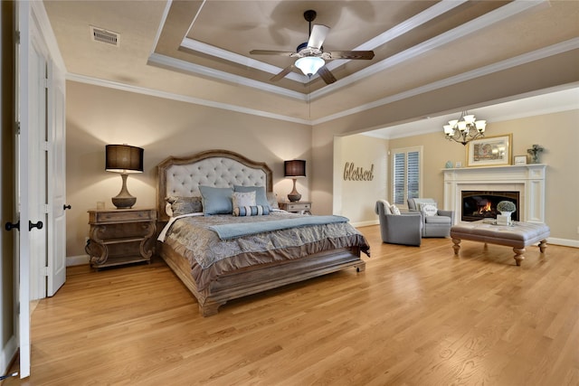 bedroom with crown molding, a raised ceiling, an inviting chandelier, and light hardwood / wood-style flooring