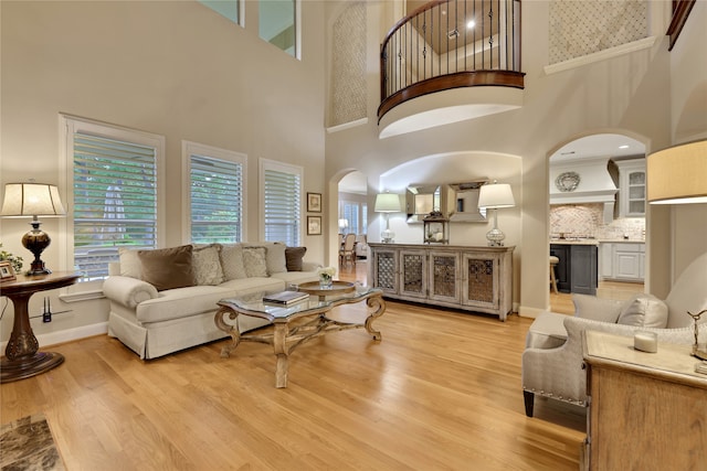 living room with light hardwood / wood-style flooring and a towering ceiling