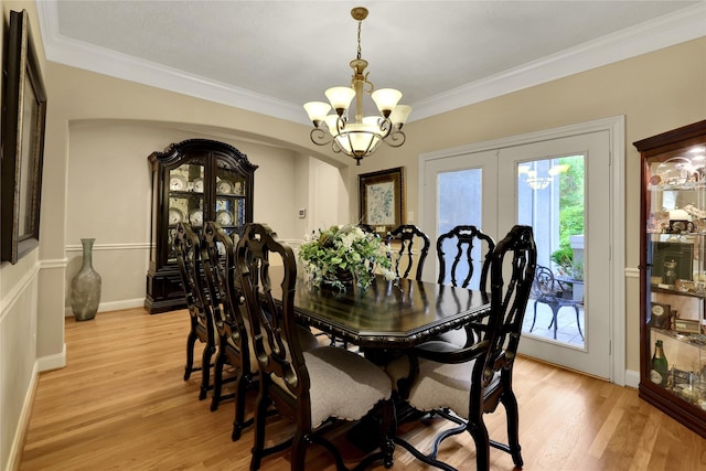 dining space with light wood-type flooring, crown molding, and a chandelier