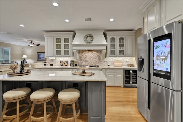 kitchen with stainless steel fridge, wine cooler, light wood-type flooring, a center island, and ceiling fan