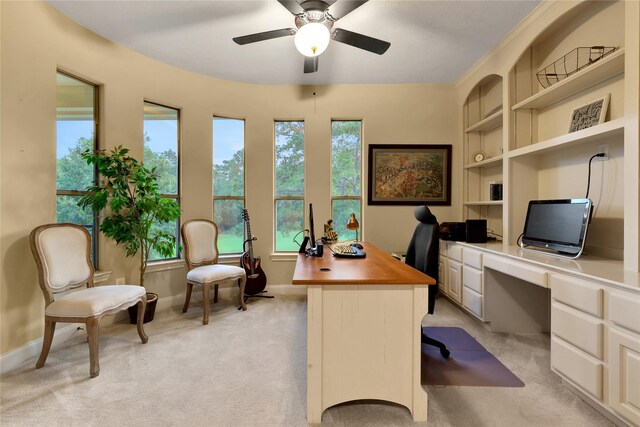 carpeted office space with ceiling fan and built in desk