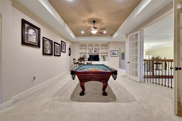 playroom with ceiling fan, built in shelves, a tray ceiling, light colored carpet, and billiards