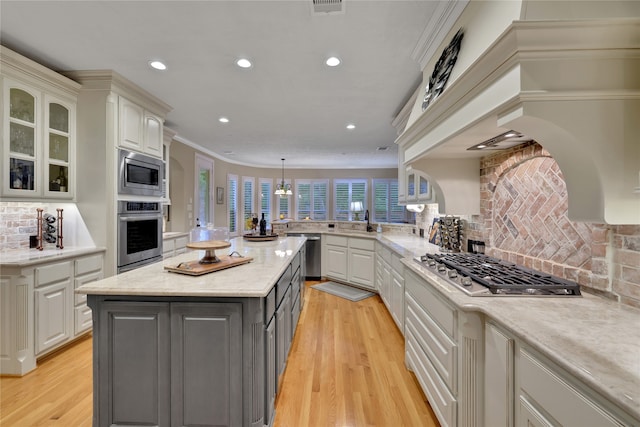 kitchen featuring stainless steel appliances, a center island, light wood-type flooring, and decorative light fixtures