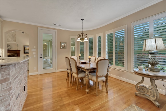 dining area featuring an inviting chandelier, light hardwood / wood-style floors, plenty of natural light, and ornamental molding