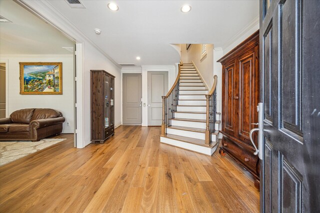 foyer featuring ornamental molding and light hardwood / wood-style flooring