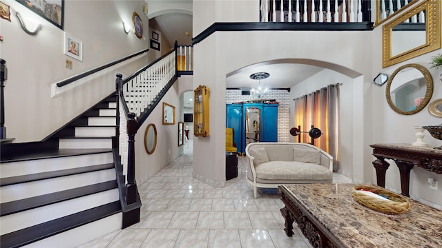 tiled entrance foyer with brick wall and a chandelier