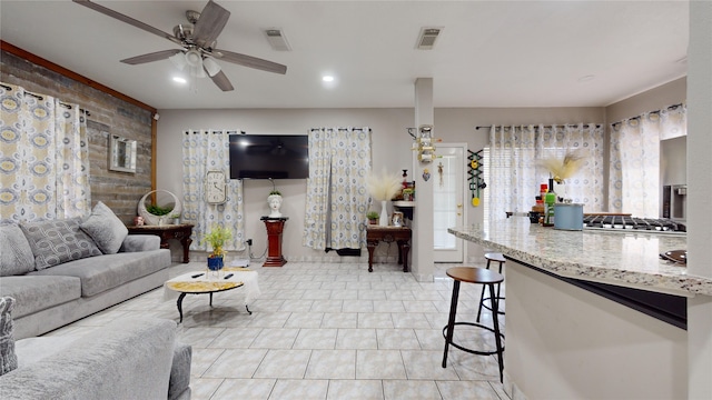 living room featuring light tile patterned flooring, brick wall, and ceiling fan