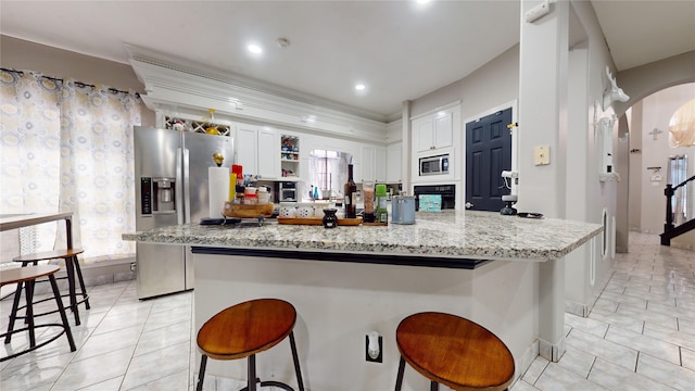 kitchen with appliances with stainless steel finishes, a kitchen island, white cabinetry, and a breakfast bar area