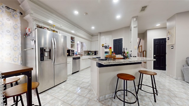 kitchen featuring white cabinets, stainless steel appliances, light tile patterned floors, and a kitchen island