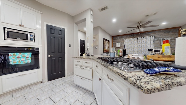 kitchen featuring stainless steel appliances, white cabinets, light tile patterned floors, light stone countertops, and ceiling fan