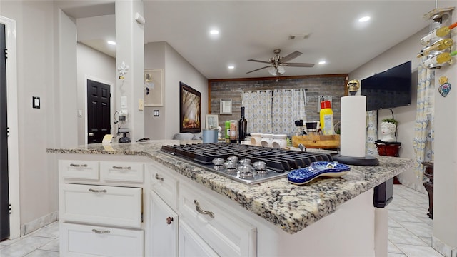 kitchen with white cabinets, light tile patterned flooring, stainless steel gas stovetop, and ceiling fan