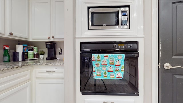 room details with oven, white cabinetry, and light stone countertops