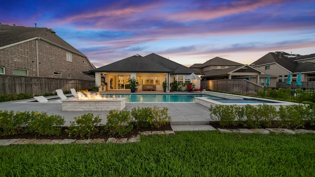 pool at dusk with a patio area and a fire pit