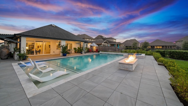 pool at dusk with a patio and an outdoor fire pit