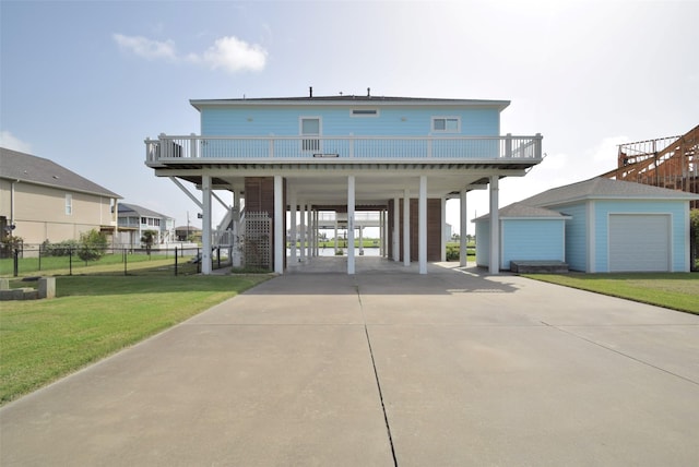 view of front of house featuring an outdoor structure, a front lawn, a carport, and a balcony