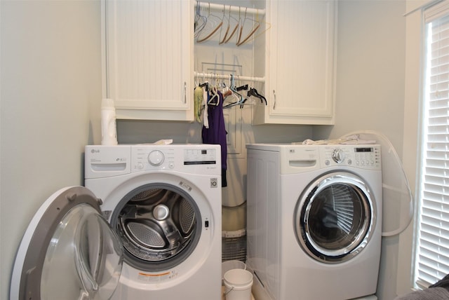 clothes washing area featuring cabinets and washing machine and clothes dryer