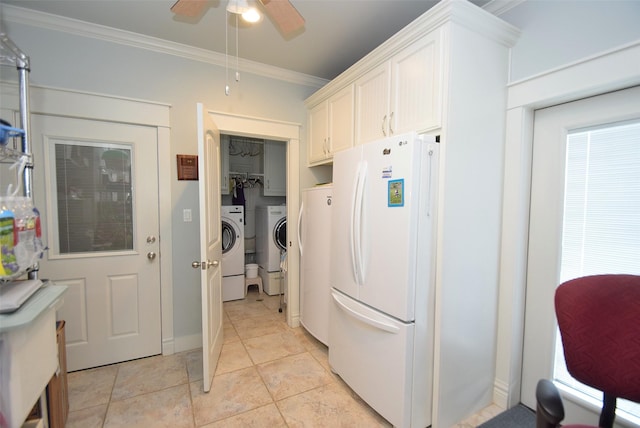 kitchen featuring white refrigerator, washing machine and clothes dryer, ornamental molding, and white cabinets