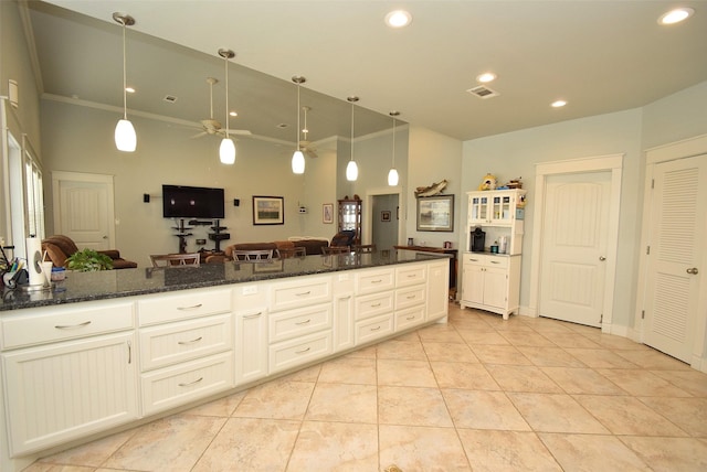 kitchen with dark stone countertops, light tile patterned floors, pendant lighting, and white cabinets