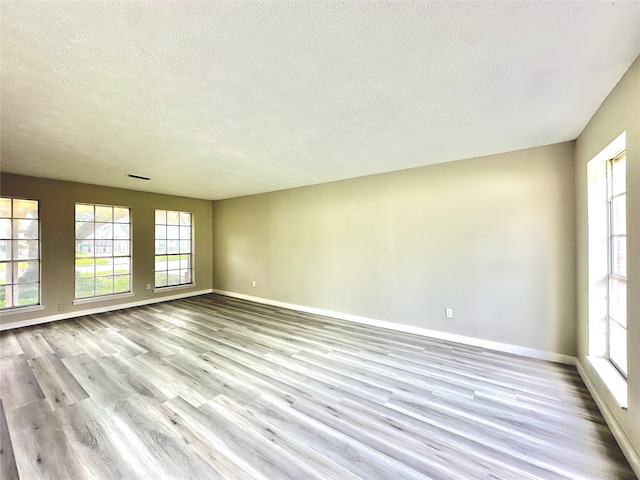 unfurnished room with light hardwood / wood-style flooring and a textured ceiling