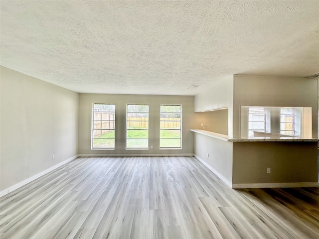 unfurnished living room with light hardwood / wood-style floors and a textured ceiling