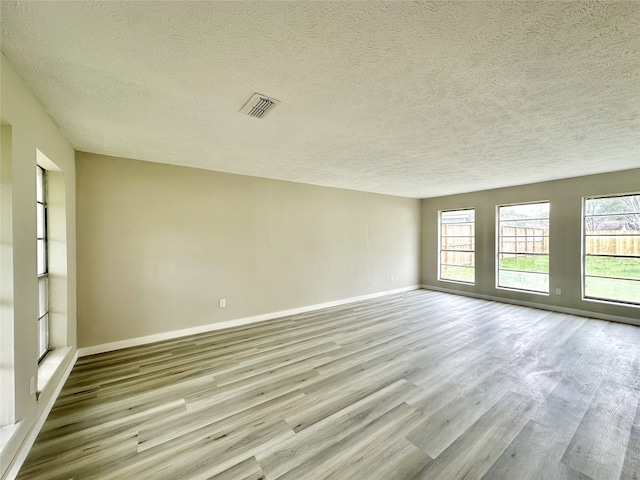 unfurnished room featuring light hardwood / wood-style flooring and a textured ceiling