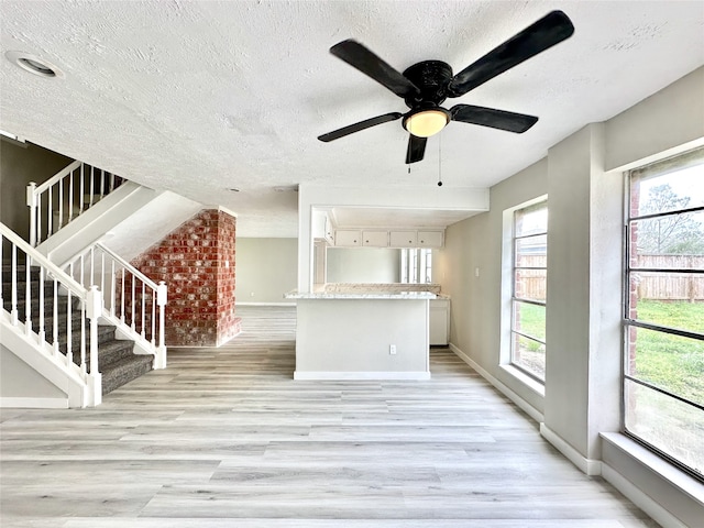 unfurnished room with light wood-type flooring, ceiling fan, and a textured ceiling