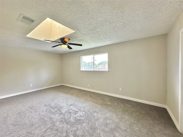 carpeted spare room featuring a skylight, a textured ceiling, and ceiling fan