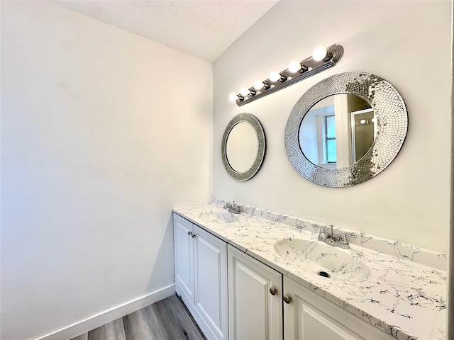 bathroom featuring wood-type flooring, a textured ceiling, and dual bowl vanity