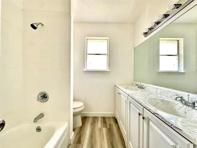 full bathroom featuring double vanity, wood-type flooring, toilet, and tiled shower / bath combo