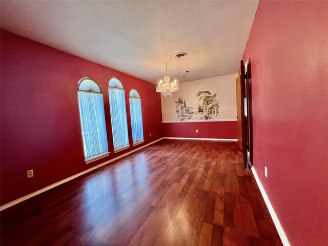 empty room featuring hardwood / wood-style floors and a chandelier