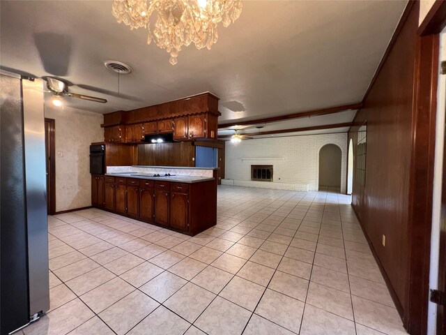 kitchen featuring light tile patterned floors, stainless steel fridge, gas stovetop, ceiling fan with notable chandelier, and oven