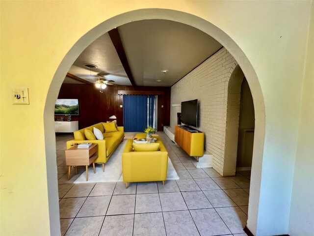 tiled living room with ceiling fan and brick wall