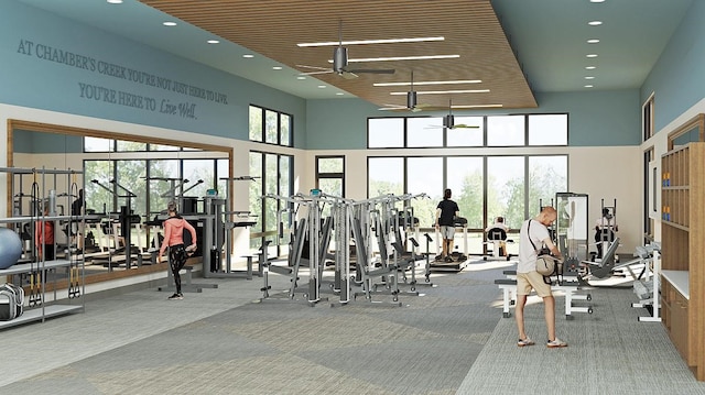 exercise room featuring carpet floors, ceiling fan, and a high ceiling