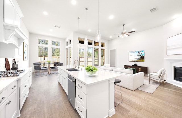 kitchen featuring sink, stainless steel appliances, light hardwood / wood-style floors, a center island with sink, and white cabinets