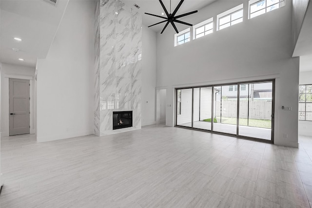 unfurnished living room with a towering ceiling, ceiling fan, and a premium fireplace