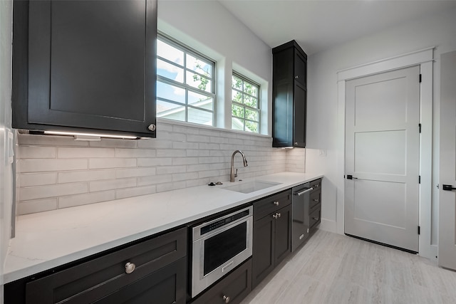 kitchen featuring decorative backsplash, stainless steel appliances, light hardwood / wood-style flooring, and sink