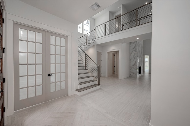 foyer with french doors, a fireplace, and a towering ceiling