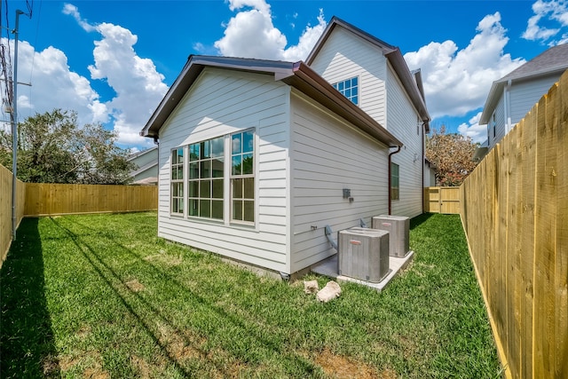 back of property featuring central AC unit and a lawn