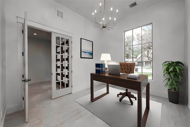 office space with a healthy amount of sunlight, light hardwood / wood-style floors, and a notable chandelier