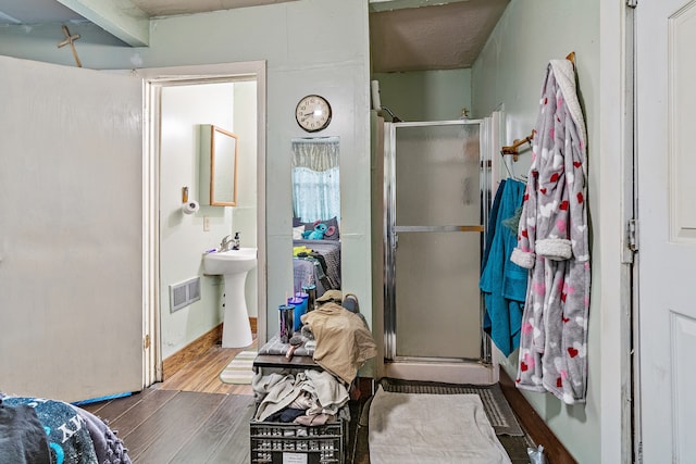 bathroom with wood-type flooring, a shower with door, and sink