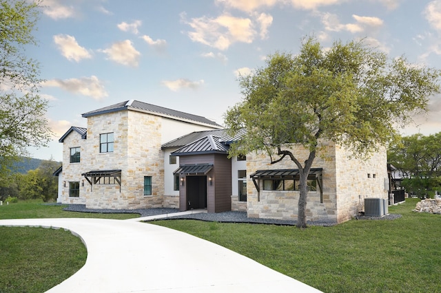 view of front of house featuring cooling unit and a front yard