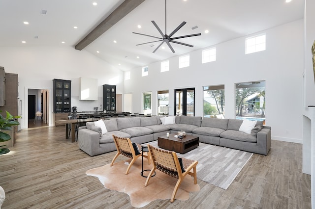 living room with light wood-type flooring, ceiling fan, and high vaulted ceiling