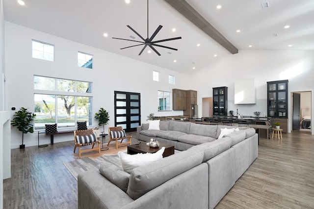 living room with light hardwood / wood-style flooring, beam ceiling, ceiling fan, and high vaulted ceiling