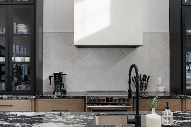 kitchen featuring dark stone counters, range, and tasteful backsplash