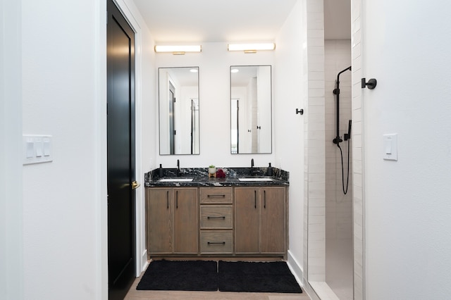 bathroom with double vanity and tiled shower