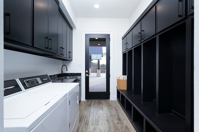 laundry room featuring washing machine and clothes dryer, sink, light hardwood / wood-style flooring, and cabinets