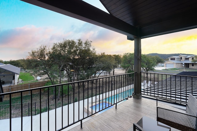 balcony at dusk with a fenced in pool