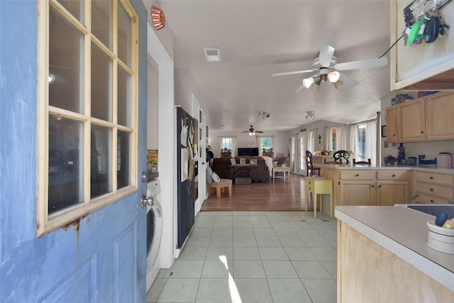 kitchen with ceiling fan, washer / dryer, light brown cabinetry, and light tile patterned floors